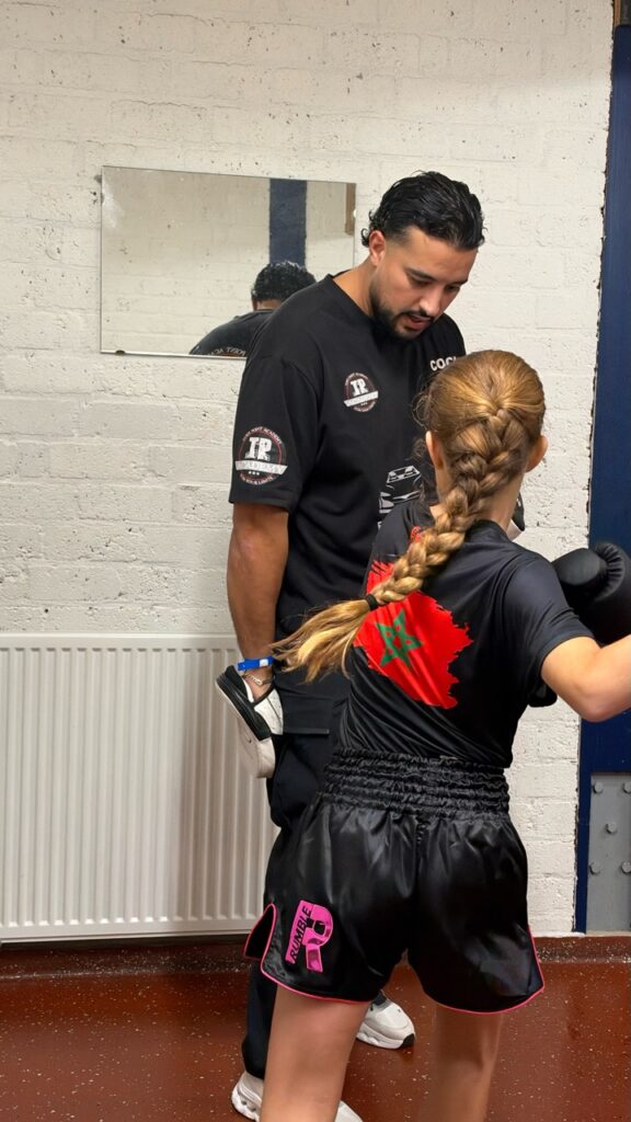 Een coach geeft een kickbokser persoonlijke uitleg tijdens de training.