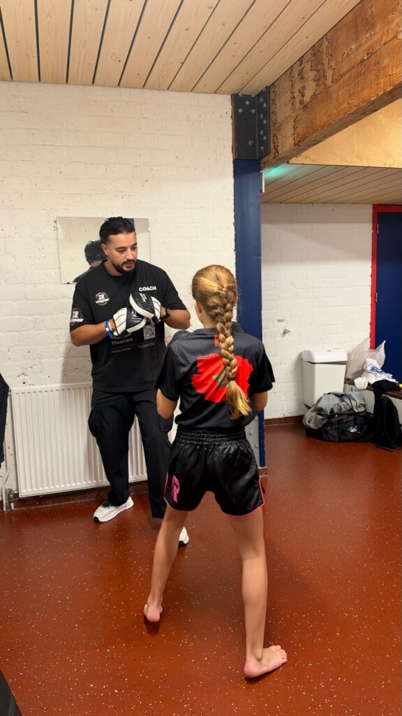 Een kickbokser oefent op de pads onder begeleiding van een TPA-coach.